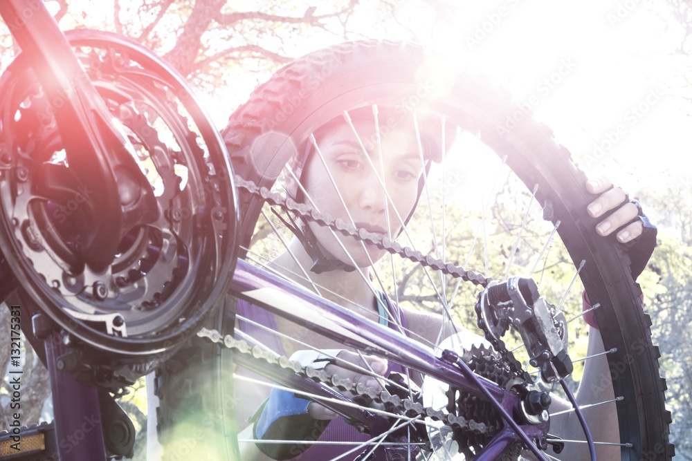 Female cyclist repairing her bicycle in park