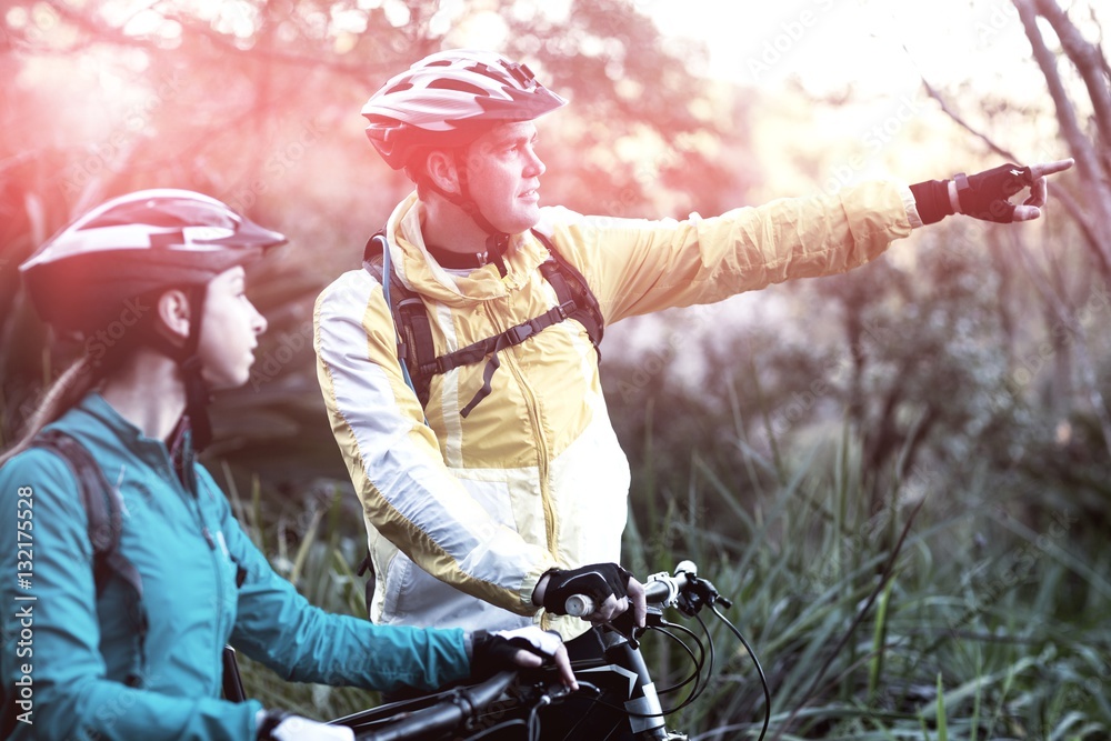 Biker couple with mountain bike pointing in distance