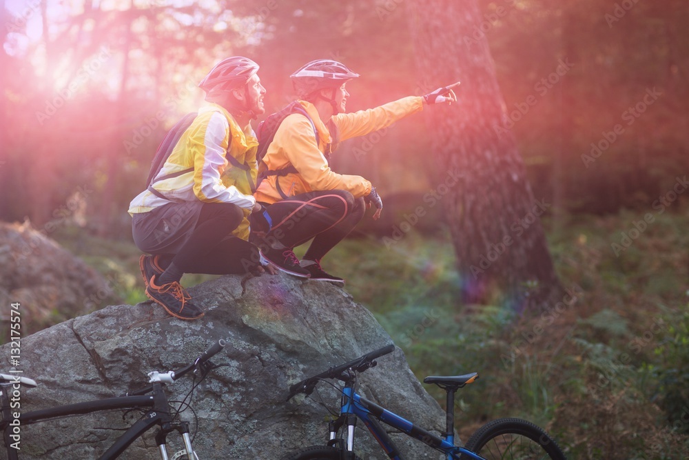 Side view of biker couple sitting and pointing in distance