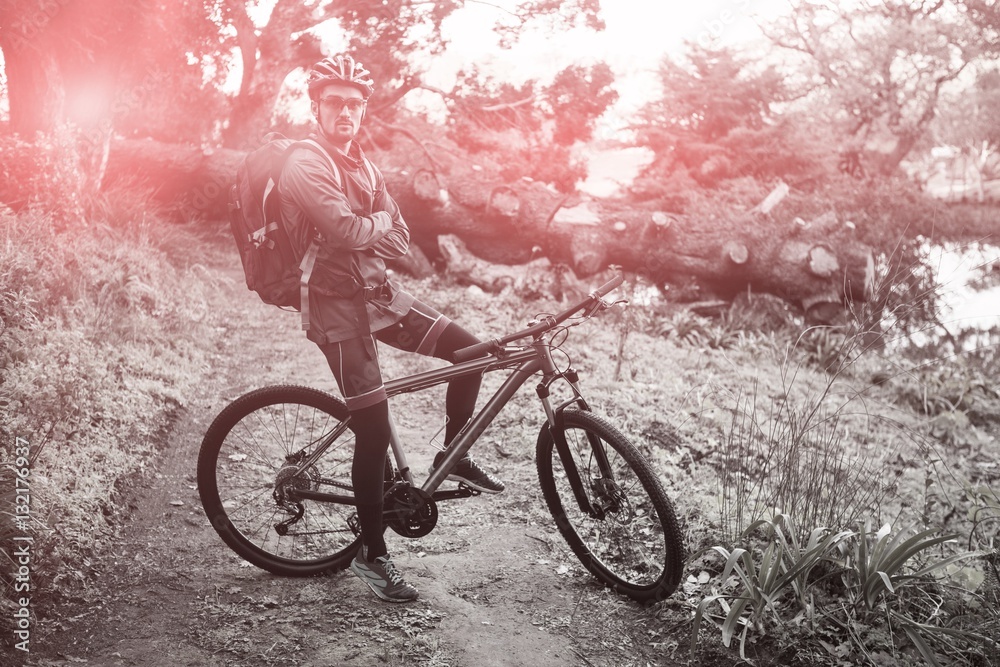 Portrait of male mountain biker with bicycle at forest