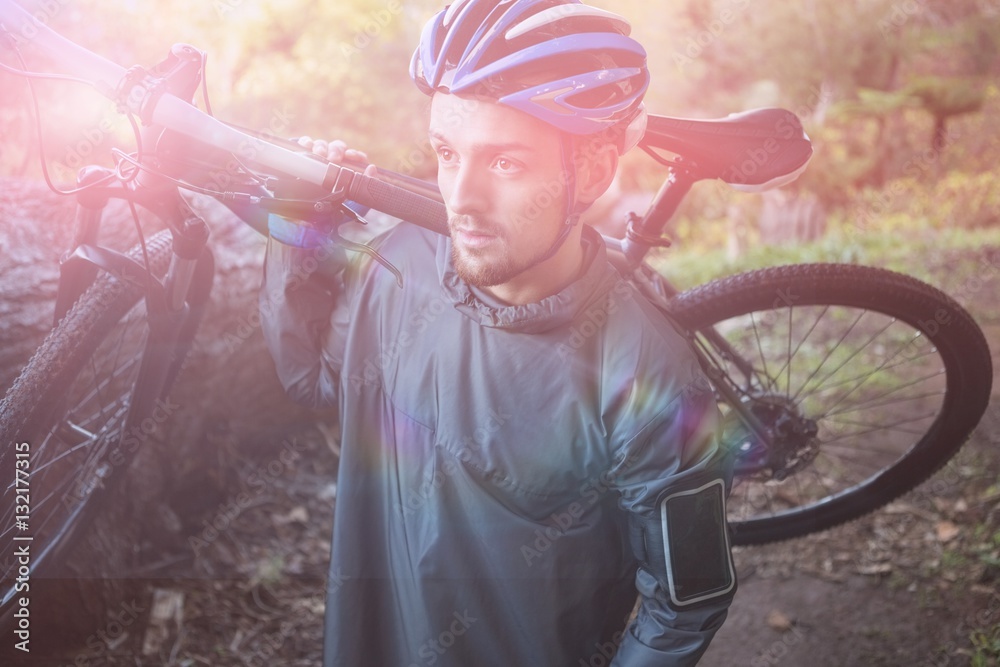 Male mountain biker carrying bicycle in forest