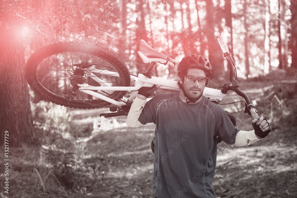 Male mountain biker carrying bicycle while walking