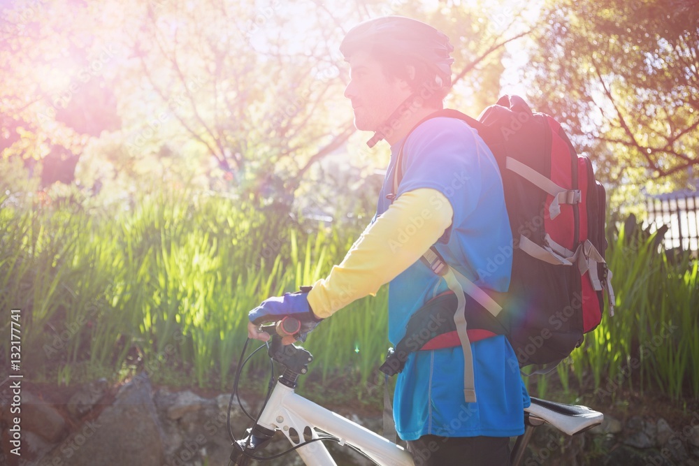 Side view of male mountain biker with bicycle in forest