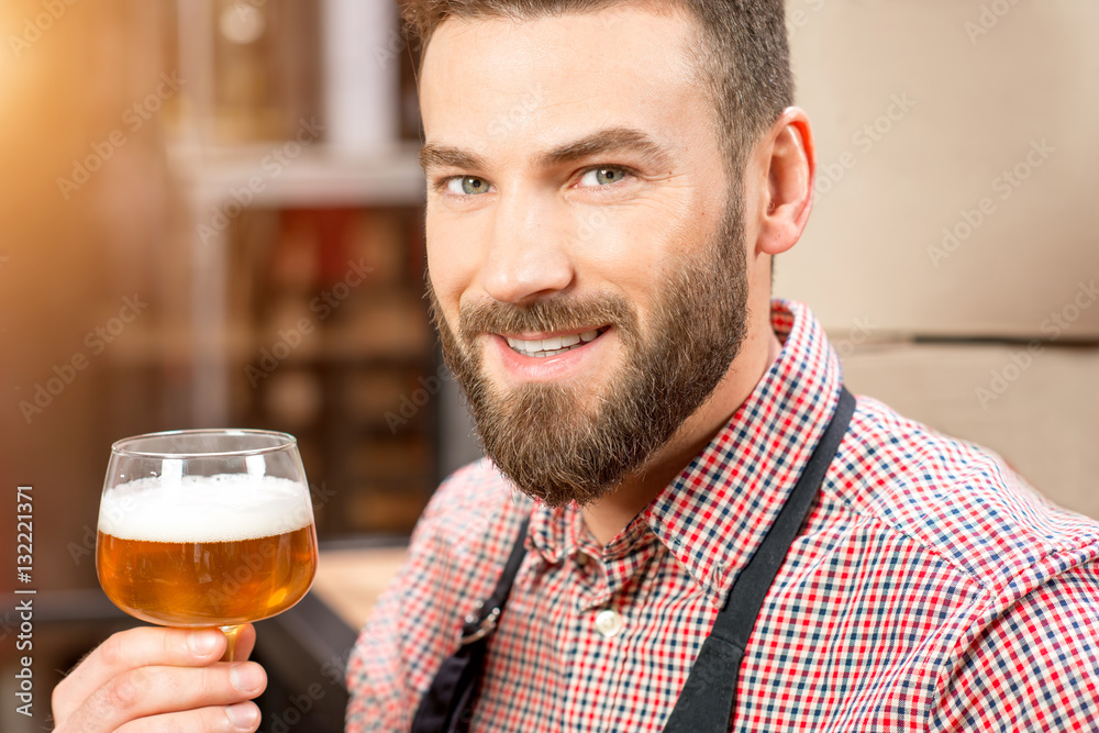 Portrait of smiling brewer with glass of beer at the manufacturing