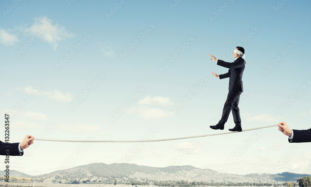 Business concept of risk support and assistance with man balancing on rope