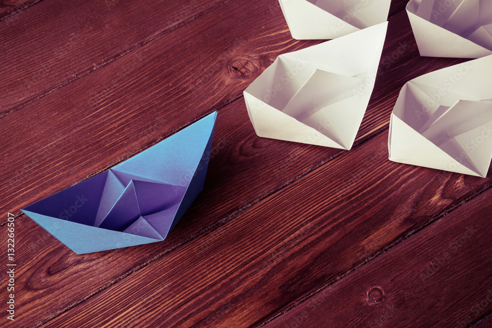 Business leadership concept with white and color paper boats on 