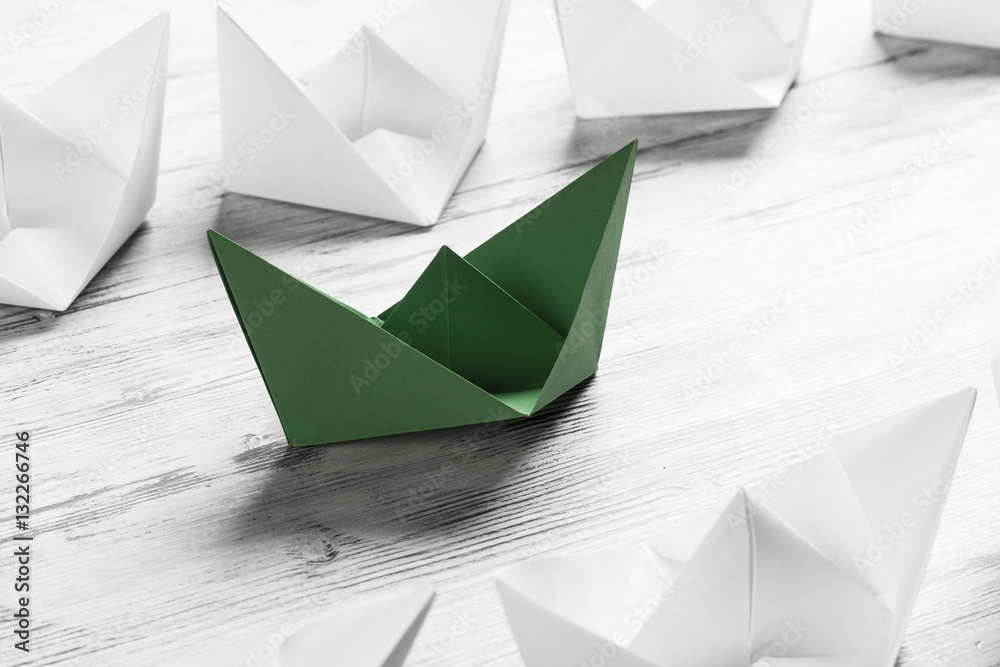 Business leadership concept with white and color paper boats on 