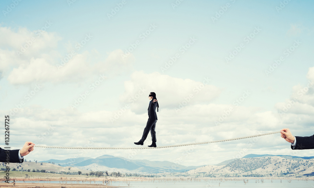 Business concept of risk support and assistance with man balancing on rope