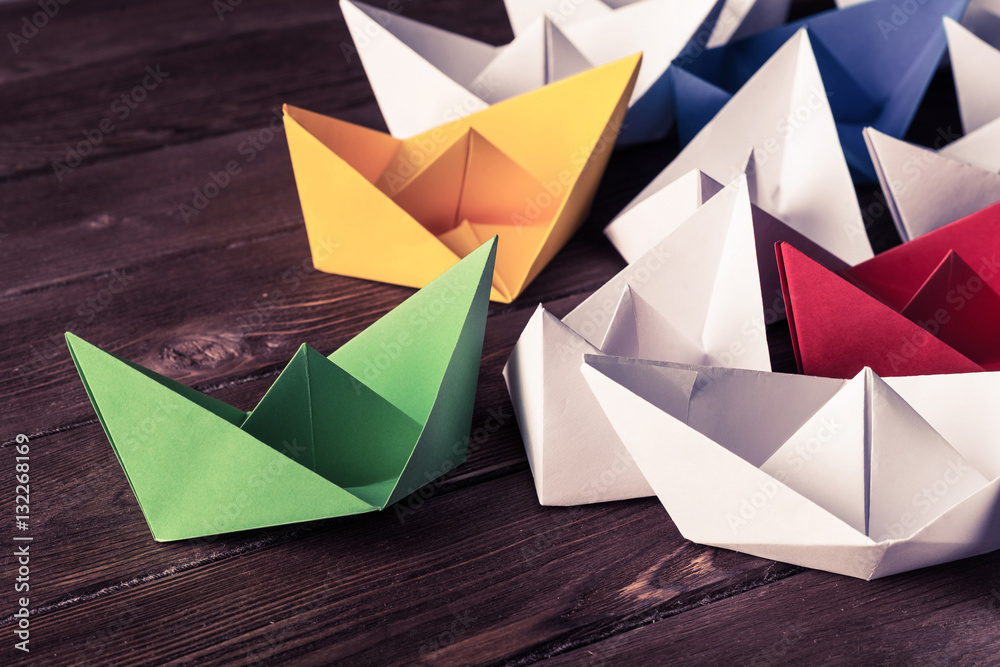 Business leadership concept with white and color paper boats on 