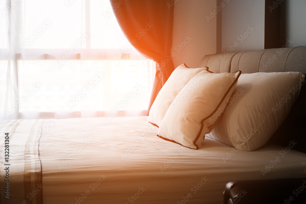 Bed maid-up with clean white pillows and bed sheets in beauty room. Close-up. Lens flair in sunlight