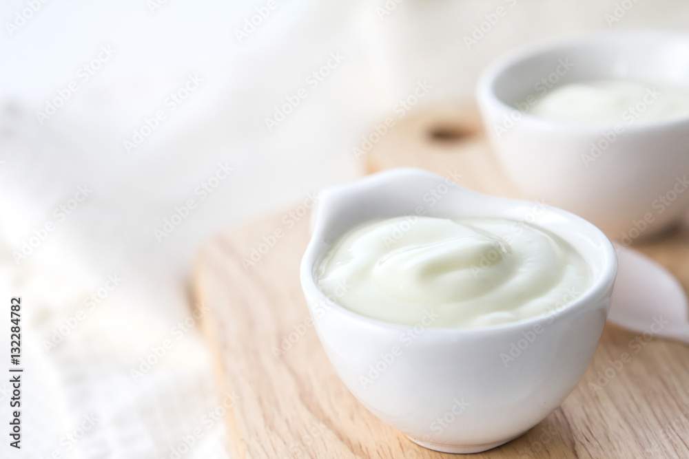 Close up white yogurt in cup on wooden plate