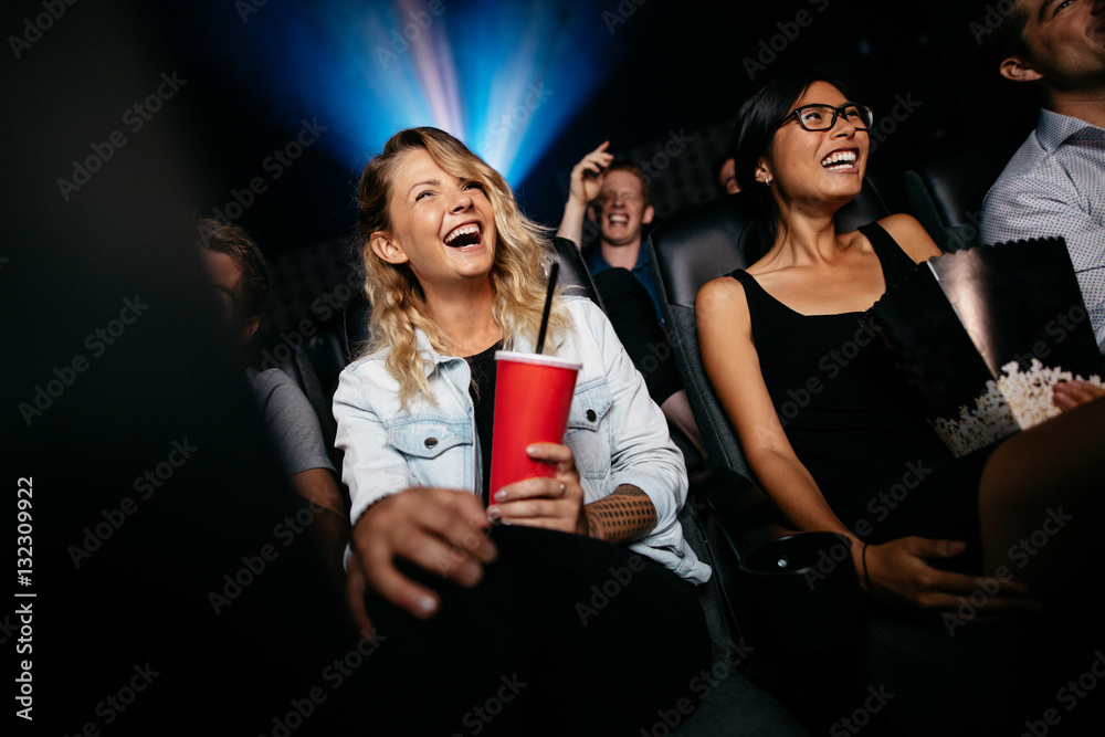 Laughing young people watching film in theater