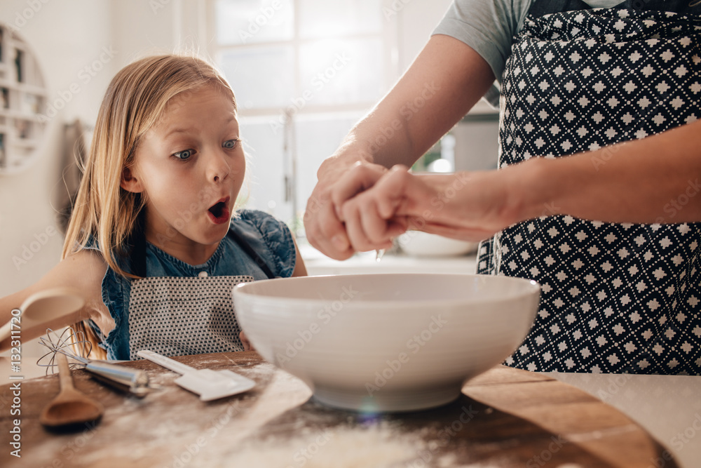 Excited young girl with mother preparing dough