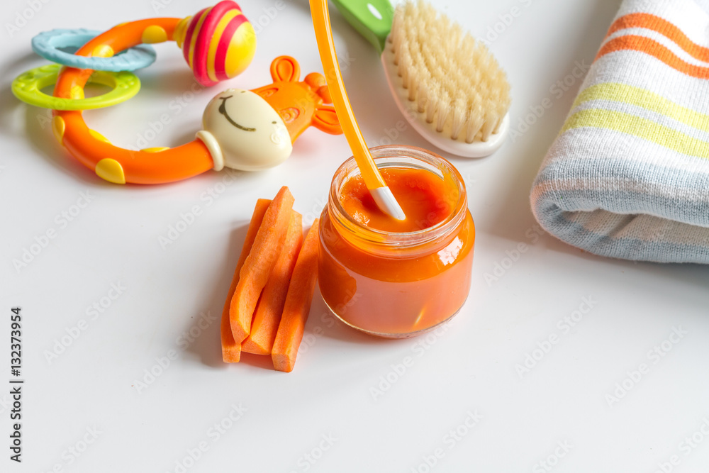 baby mashed with spoon in glass jar on white background