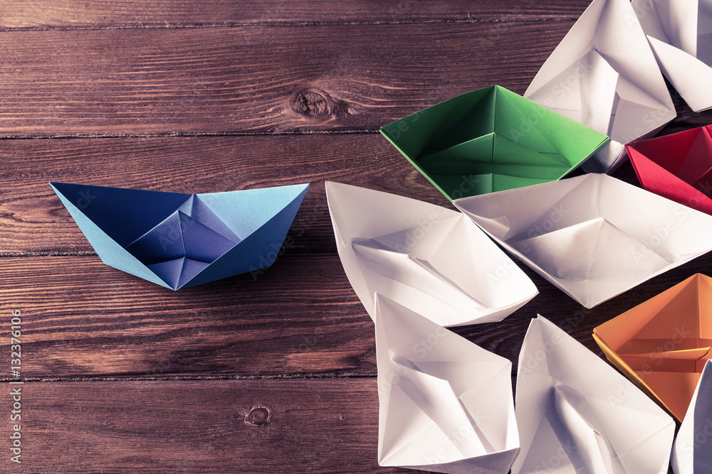 Business leadership concept with white and color paper boats on 