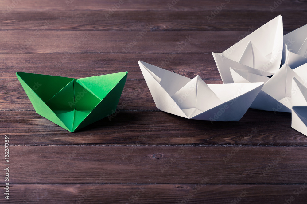 Business leadership concept with white and color paper boats on 