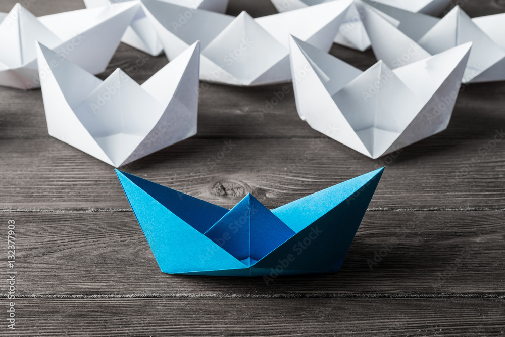 Business leadership concept with white and color paper boats on 