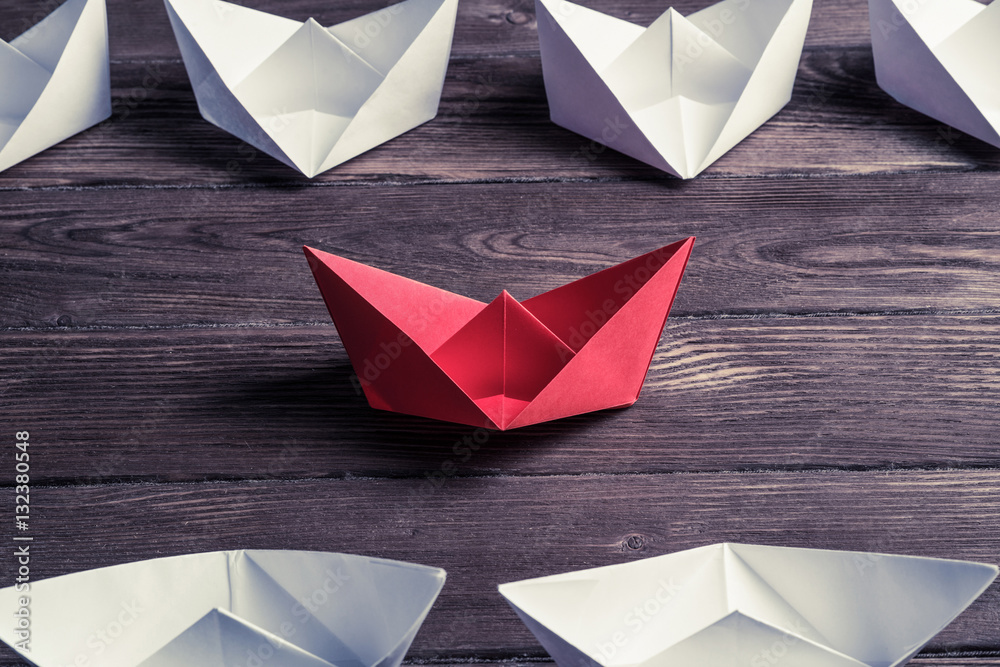 Business leadership concept with white and color paper boats on 