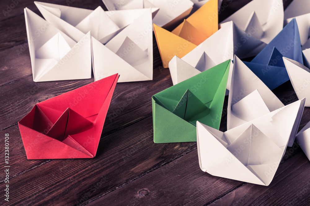 Business leadership concept with white and color paper boats on 