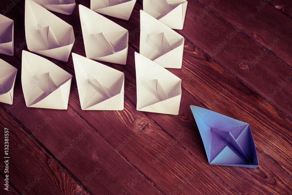 Business leadership concept with white and color paper boats on 