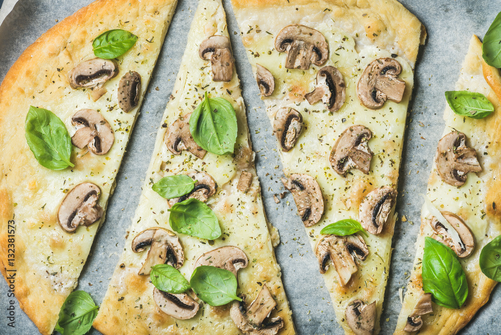 Homemade mushroom pizza with basil cut in slices on baking paper background, top view, horizontal co