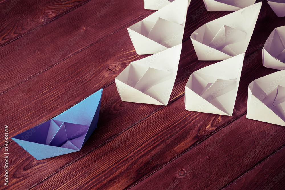 Business leadership concept with white and color paper boats on 