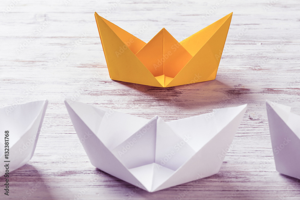 Business leadership concept with white and color paper boats on 