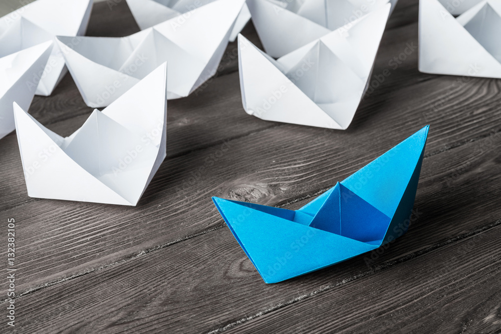 Business leadership concept with white and color paper boats on 