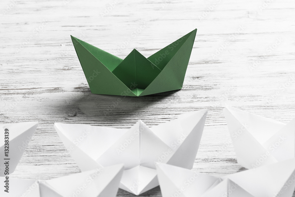 Business leadership concept with white and color paper boats on 