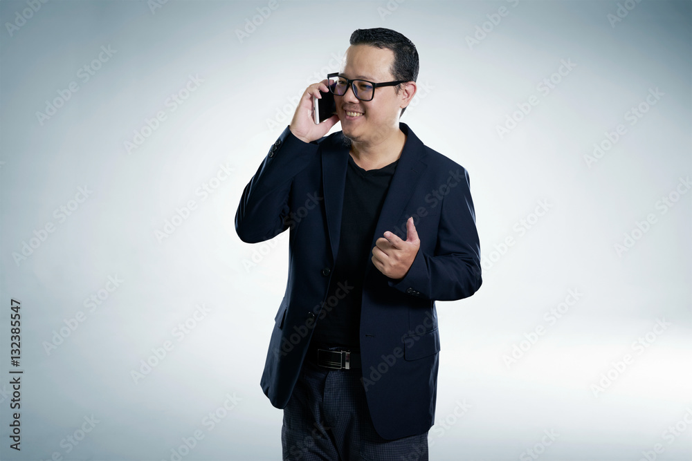 Happy smiling businessman wearing black suit and using modern smartphone with points a finger pose.