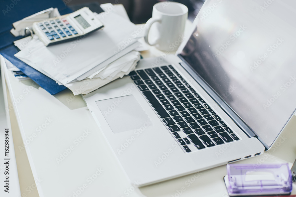 Cup of coffee, documents and laptop on the table of business person