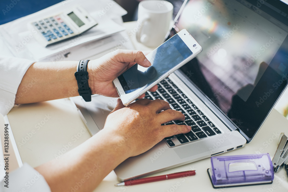 businessman hand using smart phone and keying the data to laptop,mobile payments online shopping.Sel