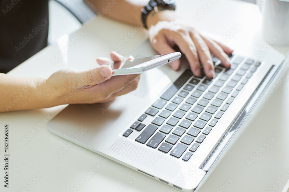 Young man hand using smart phone and laptop,close up Seleted focus.