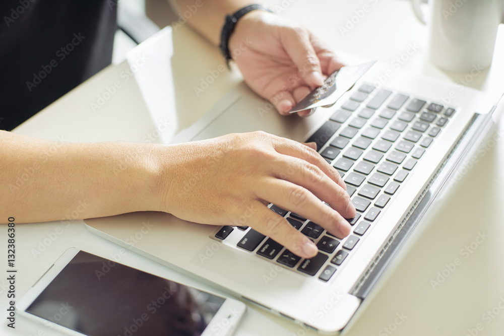 Young man holding credit card and using laptop computer. Online shopping concept,close up and select