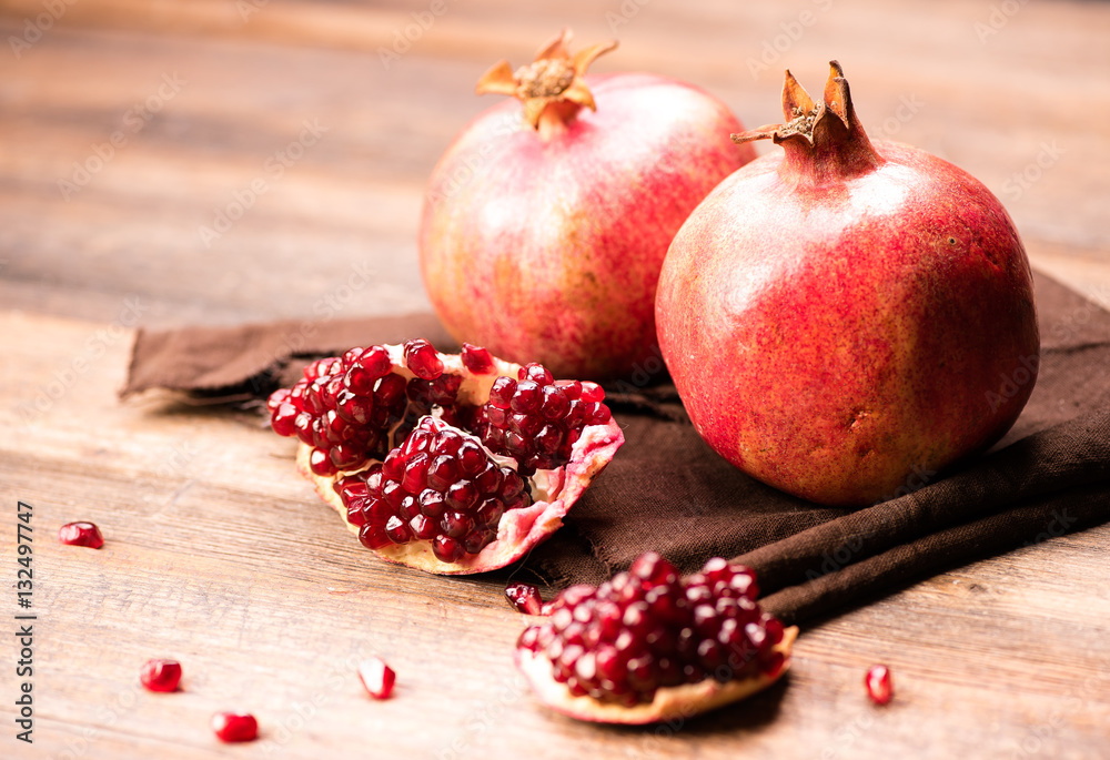 Pomegranate fruits with grains on wooden table.