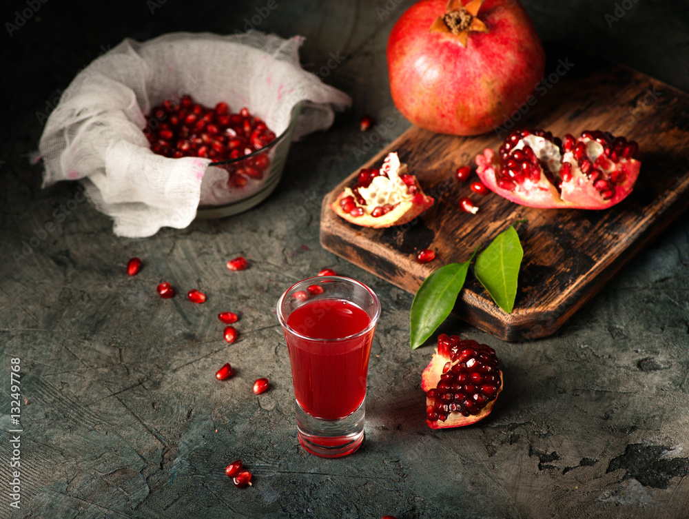 Glass of pomegranate juice. fruits with grains and leaves on the table. Make . Dark moody.