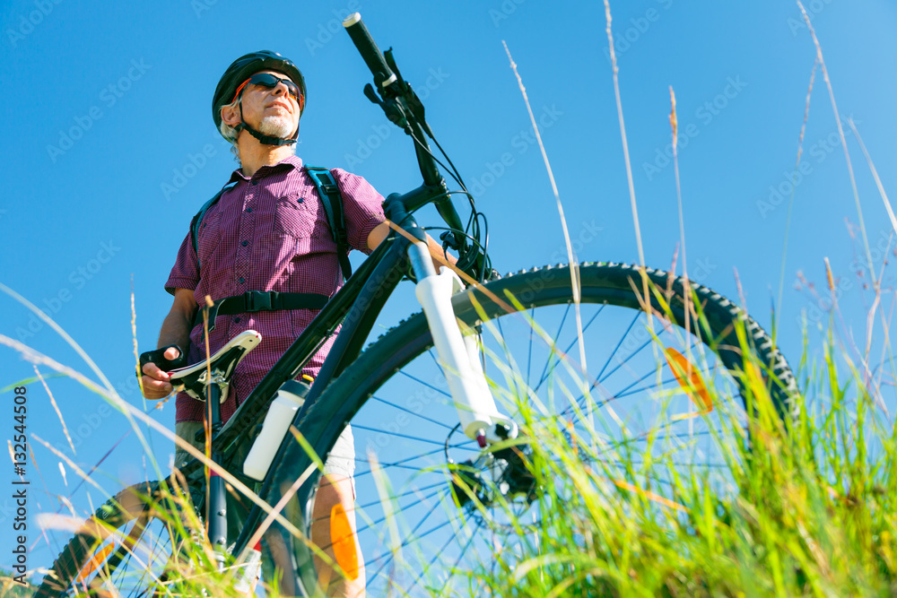 Senior With Mountain Bike Standing At Top Of A Hill