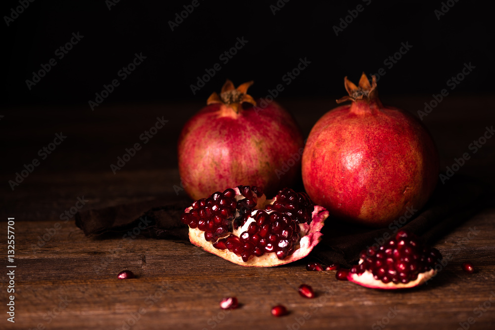 Pomegranate fruits with grains on wooden table. Dark moody. Life style.