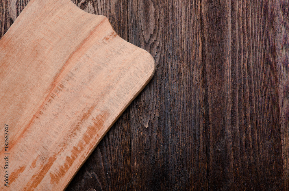 Wood board on wooden dark desktop. View from the top.