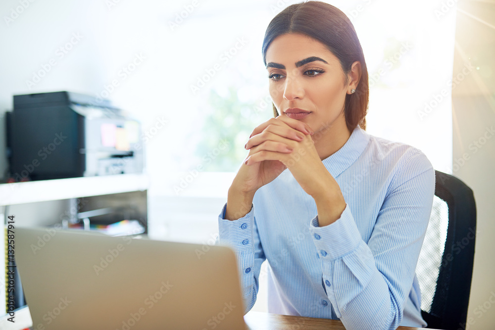 Sad single female with folded hands at laptop