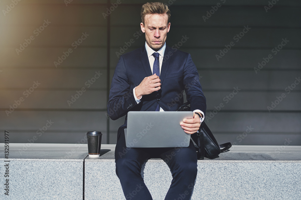 Serious handsome businessman turning on his laptop