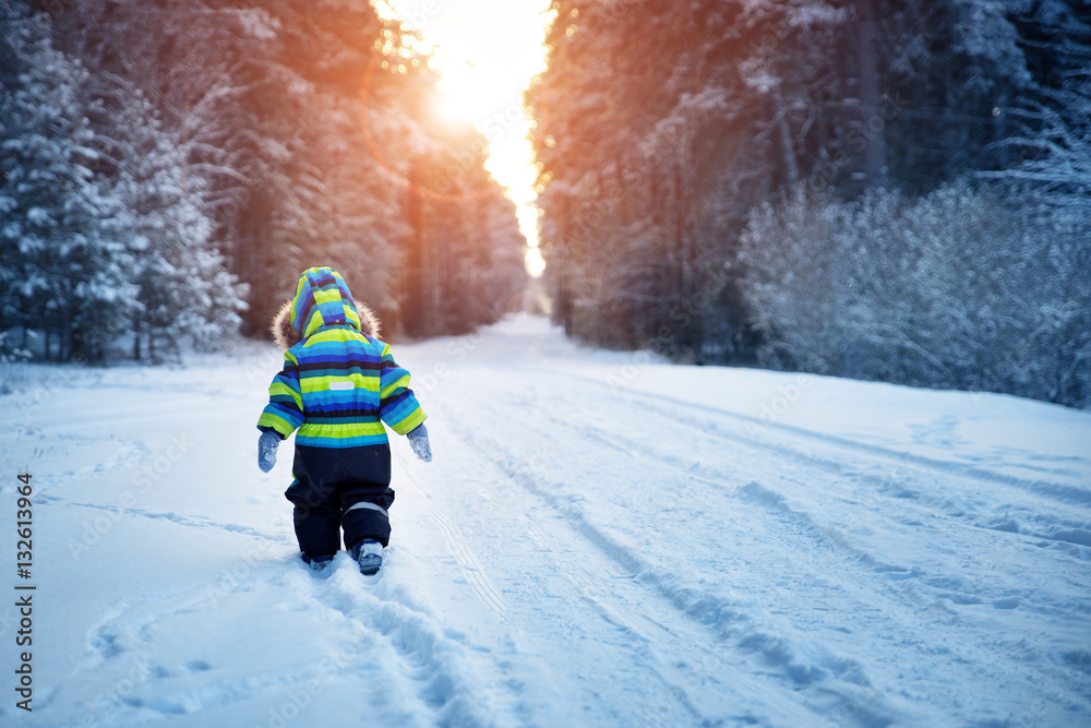 Boy in knitted hat, gloves and scarf outdoors at snowfall