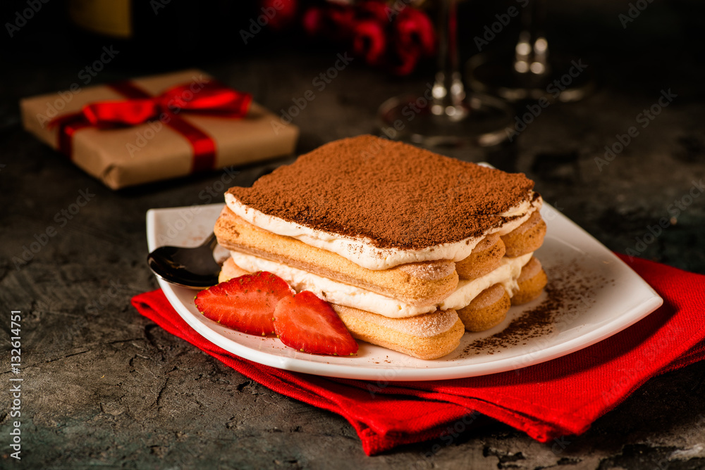 Tiramisu with strawberry on the table. Valentines concept. Dark moody style.