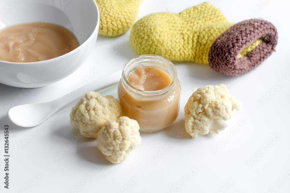 baby mashed with spoon in glass jar on white background