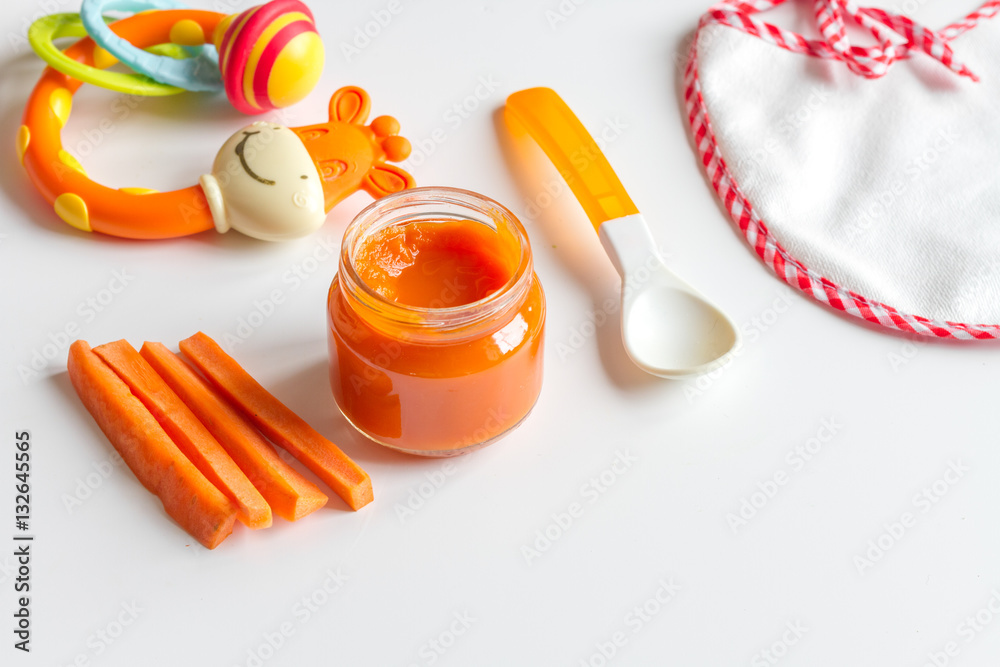 baby mashed with spoon in glass jar on white background