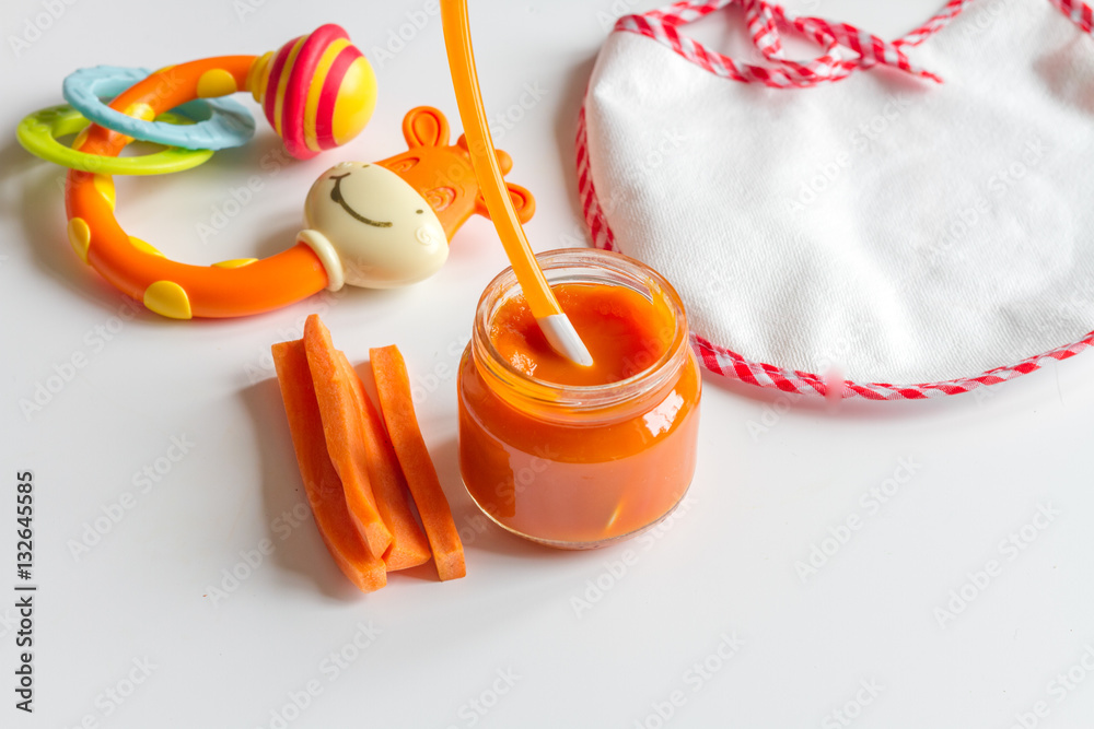 baby mashed with spoon in glass jar on white background