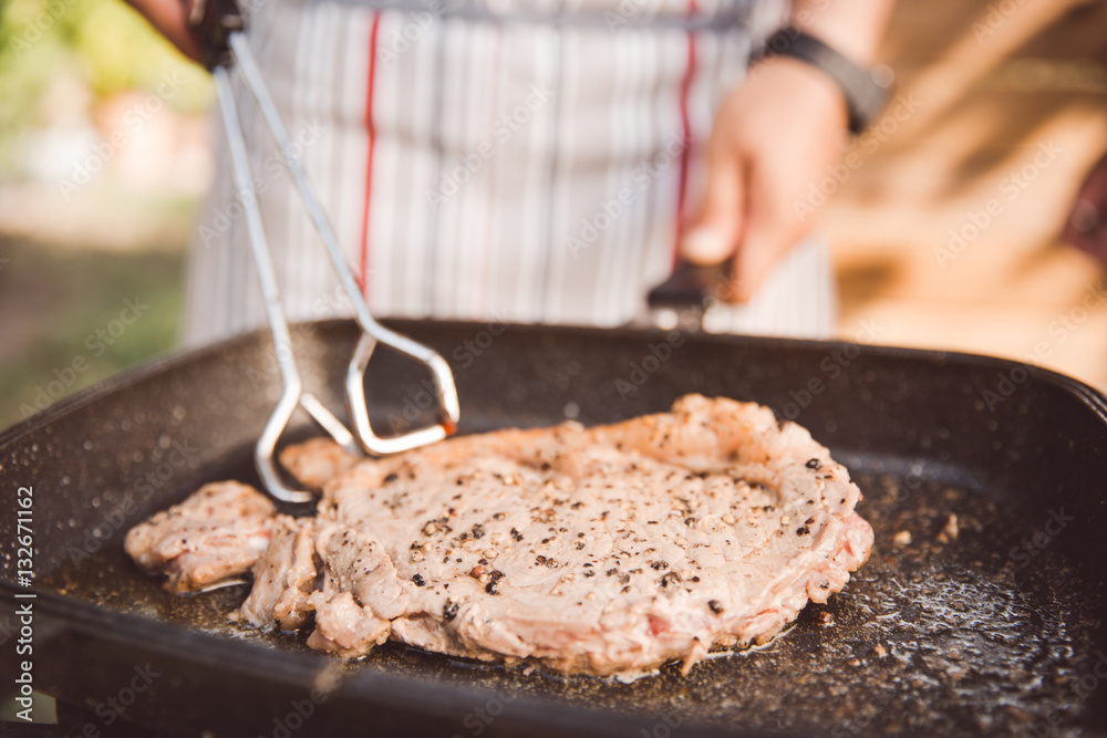 Men are cooking beef steaks are fried in a pan.