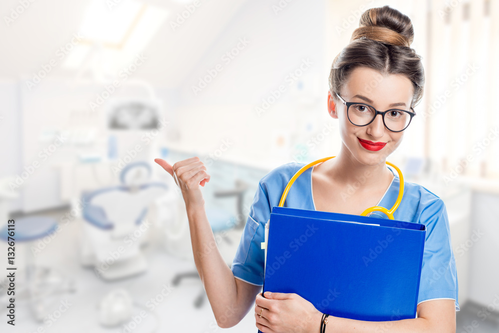 Portrait of a young female dentist in uniform with blue folder in the dental office