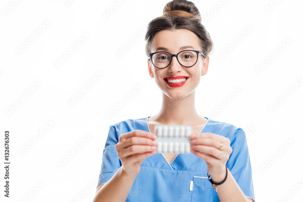 Young female doctor in uniform holding pills. Studio shot on the white background