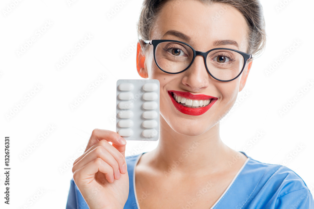 Young female doctor in uniform holding pills. Studio shot on the white background